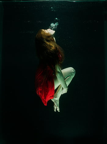 Woman in red dress captured gracefully underwater, creating an ethereal and artistic scene. HD phone wallpaper