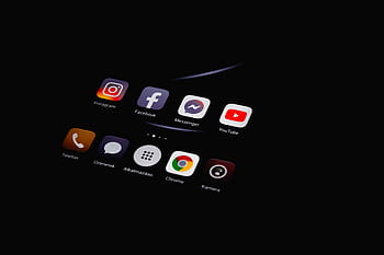Close-up of smart displaying popular social media apps in dim lighting. HD wallpaper
