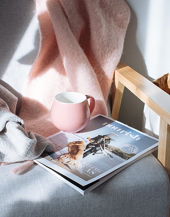 A warm scene featuring a pink mug and magazine on a wooden chair, bathed in sunlight. HD phone wallpaper