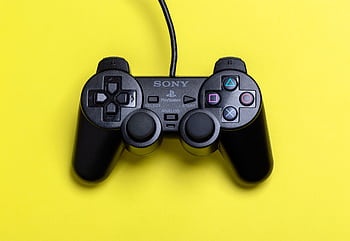 A close-up view of a black gaming controller set against a vibrant yellow background, highlighting modern gaming technology. HD wallpaper