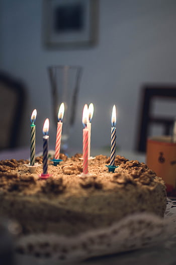 Close-up of a delicious birtay cake with colorful lit candles in a cozy setting. HD phone wallpaper