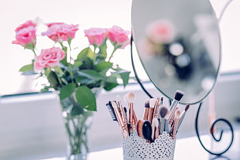 A delicate arrangement of roses with makeup brushes and a mirror, perfect for beauty and decor themes. HD wallpaper