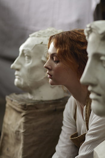 Pensive woman sitting with classical sculptures, reflecting beauty and art. HD phone wallpaper