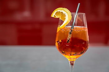 Bright Aperol spritz with lemon slice on a glass, perfect for summer refreshment. HD wallpaper