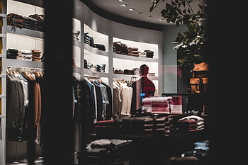 Stylish interior of a modern clothing store featuring elegant apparel on racks and shelves. HD wallpaper