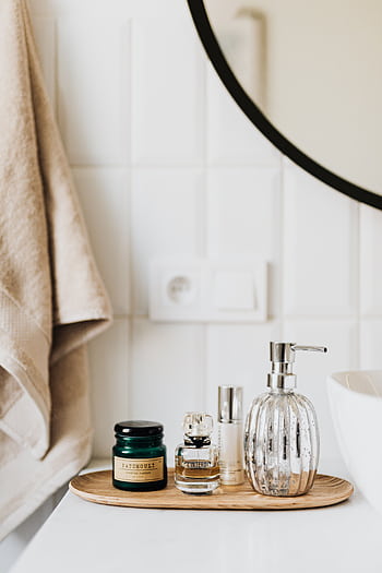 A stylish bathroom setup featuring luxury toiletries and a round mirror. HD phone wallpaper