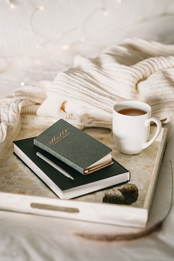 Relaxing setup with a cup of tea and journal on a bed, perfect for a cozy winter afternoon. HD phone wallpaper