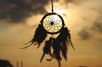 Silhouette of a dreamcatcher hanging against a serene sunset sky. HD wallpaper