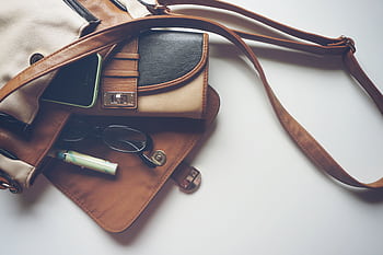 Overhead view of leather bag with eyeglasses, wallet, and smart laid out. HD wallpaper