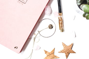 Stylish flat lay featuring a pink journal, gold pen, bracelet, and decorative stars. HD wallpaper