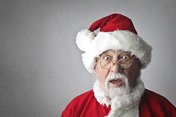 A surprised Santa Claus in traditional red outfit and glasses, expressing joy and wonder. HD wallpaper