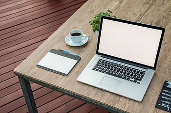 A minimalist outdoor workstation with laptop, coffee, and tablet on a rustic table. HD wallpaper
