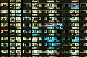 Night view of a modern apartment building with illuminated windows, showcasing urban life. HD wallpaper