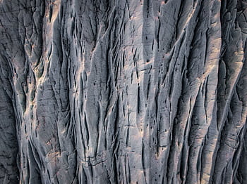 A detailed aerial view of a rugged rock surface with natural erosion patterns in Iceland. HD wallpaper