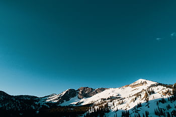 A breathtaking view of snow-covered mountains with a clear blue sky, showcasing a serene winter landscape. HD wallpaper