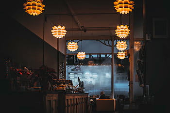 Warm-lit restaurant interior showcasing cozy ambiance and decorative hanging lamps. HD wallpaper