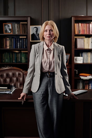 Professional businesswoman standing confidently in a classic office, exuding leadership and success. HD phone wallpaper
