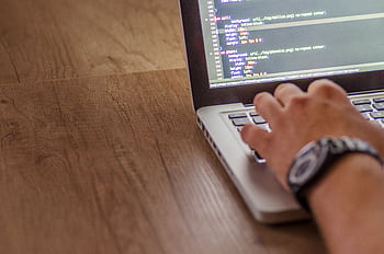 Close-up of a person coding on a laptop, showcasing web development and programming concepts. HD wallpaper