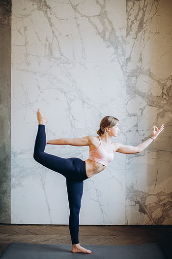 A woman performing a yoga pose indoors, showcasing flexibility and balance for wellbeing. HD phone wallpaper