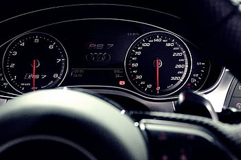 Close-up view of a luxury car dashboard featuring speedometer and gauges at night. HD wallpaper