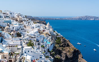 Beautiful Santorini houses overlooking the Aegean Sea on a sunny day. HD wallpaper