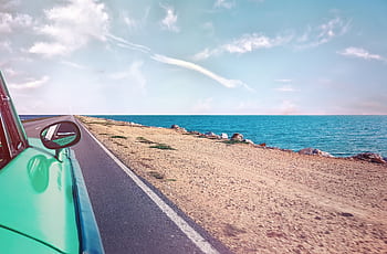 A scenic road trip in a vintage car along a stunning seaside landscape under a clear blue sky. HD wallpaper