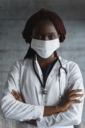 Portrait of a confident female doctor wearing a mask and stethoscope, arms crossed. HD phone wallpaper