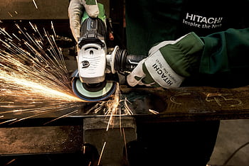 Close-up of a skilled worker using a grinder with sparks flying in a metal workshop. HD wallpaper