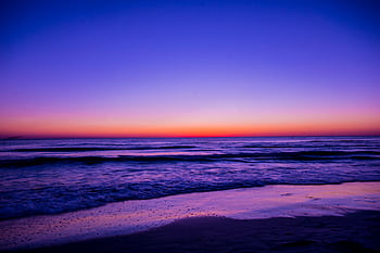Serene beach sunset with vibrant colors reflecting on the water and waves. HD wallpaper