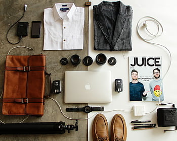 Neatly arranged travel essentials for men including clothing, tech gear, and a magazine. HD wallpaper