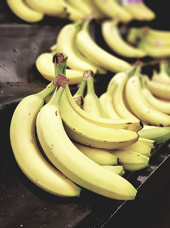 Close-up shot of vibrant yellow bananas on display, highlighting freshness and nutrition. HD phone wallpaper