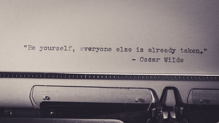 Vintage typewriter displaying Oscar Wilde's quote 'Be yourself, everyone else is already taken.' HD wallpaper