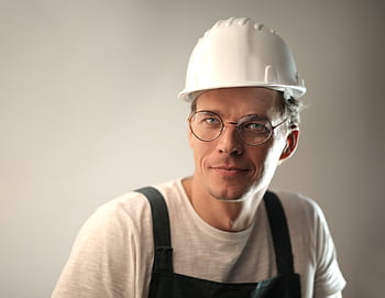 Portrait of a cheerful construction worker wearing a hard hat and glasses. HD wallpaper