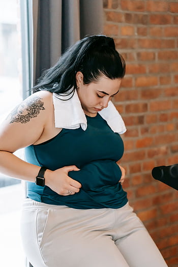 Young woman in activewear at the gym, reflecting on fitness journey and body transformation goals. HD phone wallpaper