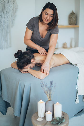 A serene spa setting with a therapist giving a back massage to a female client for relaxation. HD phone wallpaper
