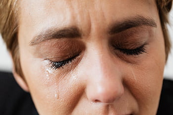 Emotional close-up of a woman's face with closed eyes and tears expressing distress. HD wallpaper