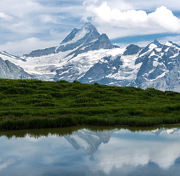 Breathtaking view of snowy mountains reflecting in a tranquil lake in Grindelwald, Switzerland. HD wallpaper