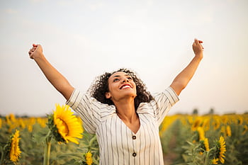 Joyful woman with arms raised in a sunflower field, embracing dom and happiness. HD wallpaper