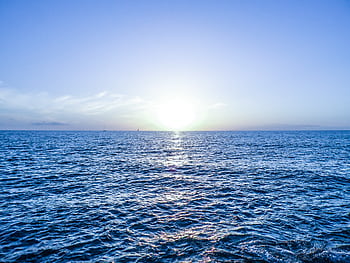 Capture the serene beauty of a sunrise over the ocean in Arona, Spain, with vibrant reflections. HD wallpaper