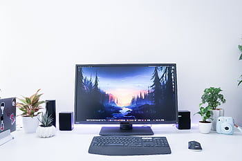 Contemporary desk setup featuring a monitor, plants, and electronic devices in a sleek, minimalist design. HD wallpaper