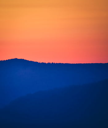Stunning sunset scene with colorful sky over rolling mountain hills, creating a peaceful landscape. HD phone wallpaper