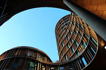 Innovative modern architecture showcasing curved glass structures against a clear blue sky. HD wallpaper