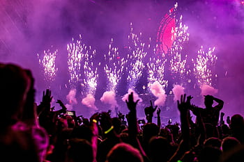 Vibrant EDM concert scene with fireworks, smoke, and enthusiastic crowd enjoying the music. HD wallpaper