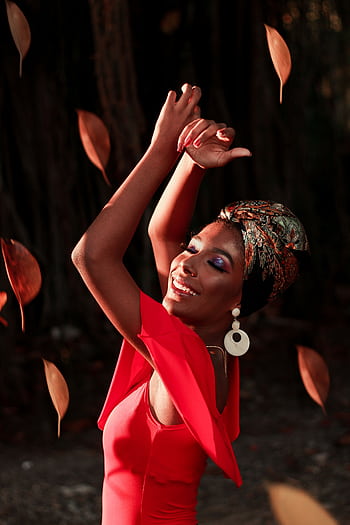 Joyful woman dancing outdoors, surrounded by falling leaves at sunset. HD phone wallpaper
