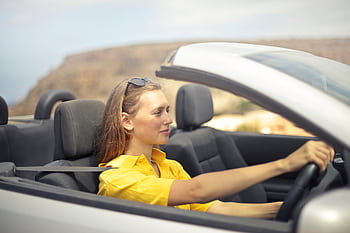 A young woman enjoys driving a convertible on a sunny day in Malta. HD wallpaper