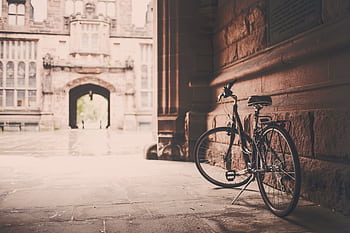 An elegant vintage bicycle rests against an old stone building, exuding nostalgic charm. HD wallpaper