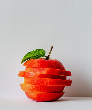 Artistic stack of sliced apple pieces with a fresh green leaf. HD phone wallpaper