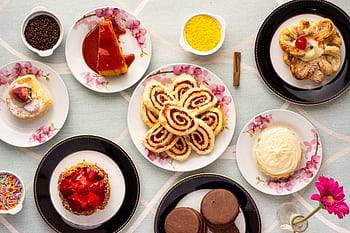 An assortment of mouthwatering pastries displayed on floral plates for a delightful treat. HD wallpaper