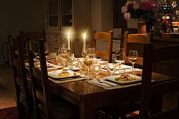 A cozy, candlelit table set for an elegant dinner, featuring fine tableware and a warm ambiance. HD wallpaper