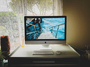 Sleek and modern computer setup on a desk by a window, showcasing productivity. HD wallpaper